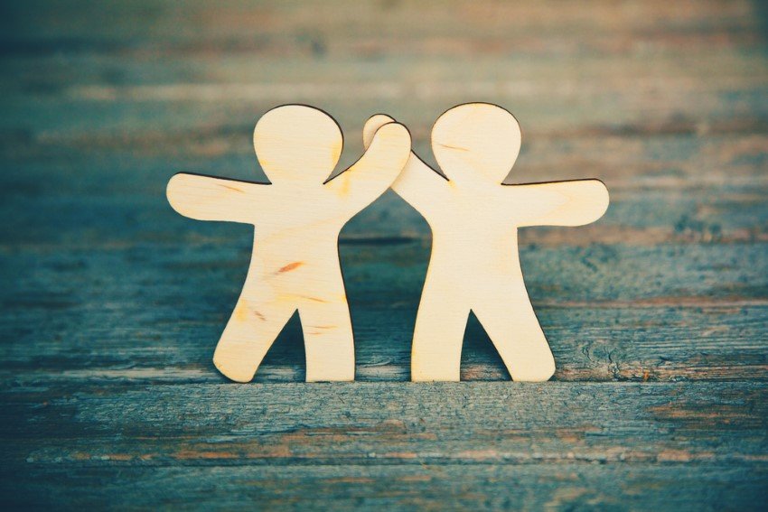 Two Miniature Figures Made Of Wood Give Each Other High Five Symbolizing Friendship And Love
